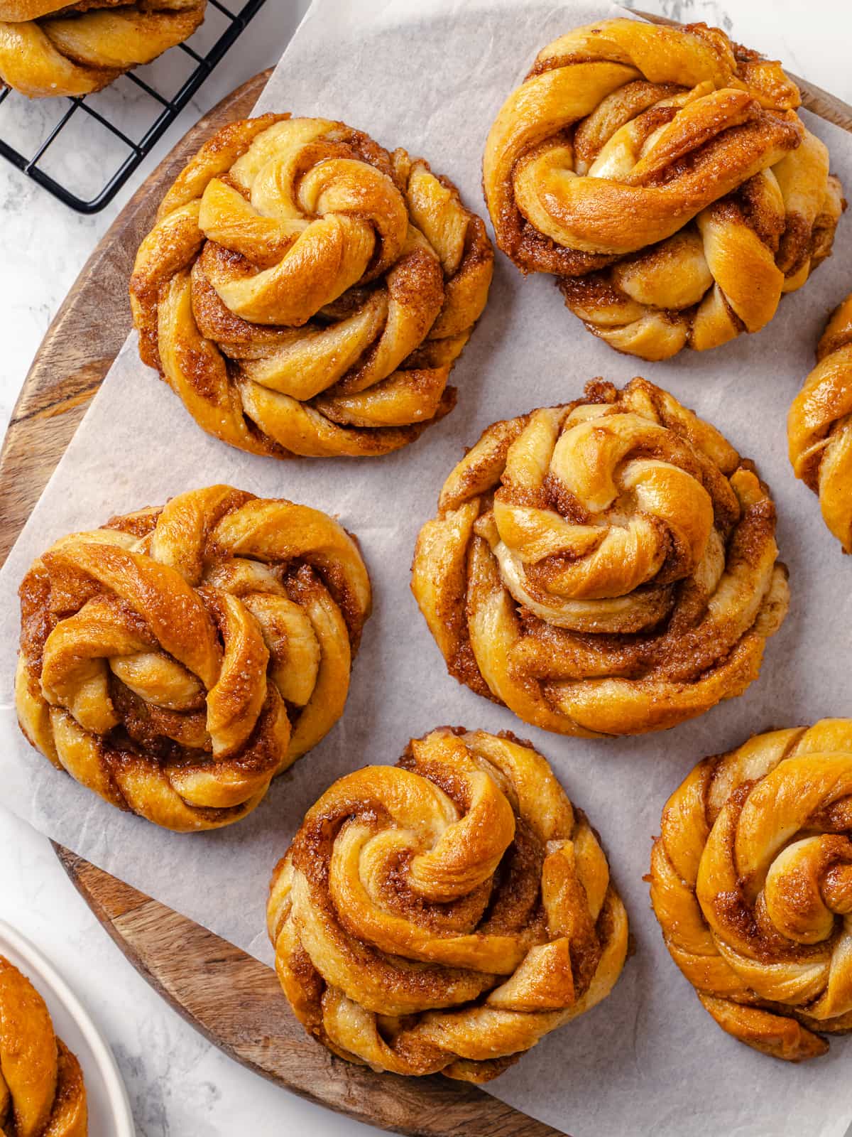 A large batch of cardamom buns arranged on a tray, evenly baked and golden brown.