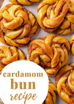 Soft cardamom buns arranged on parchment paper, showing their twisted layers and golden brown crusts.