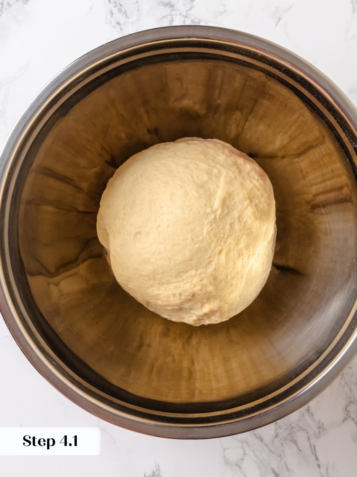 Elastic cardamom dough gathered into a smooth ball inside a lightly greased bowl.