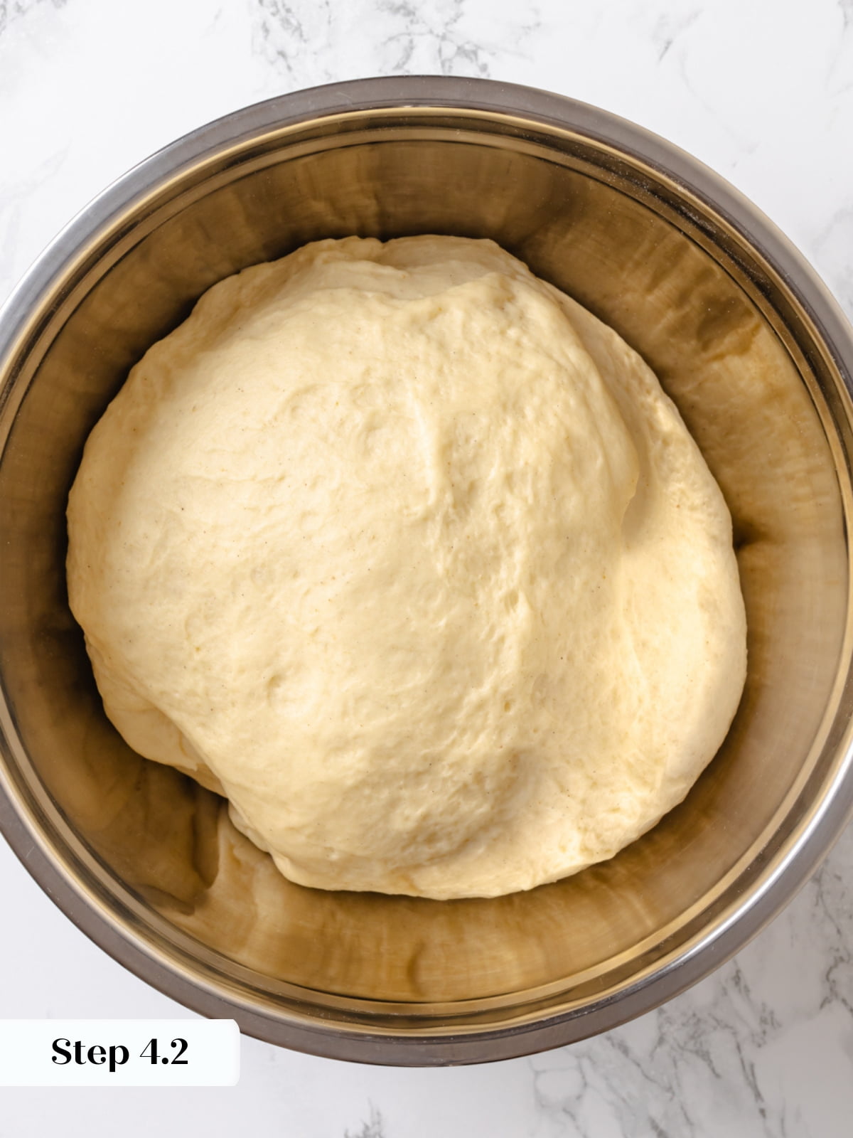 Dough resting in a bowl covered loosely while rising until doubled in size.