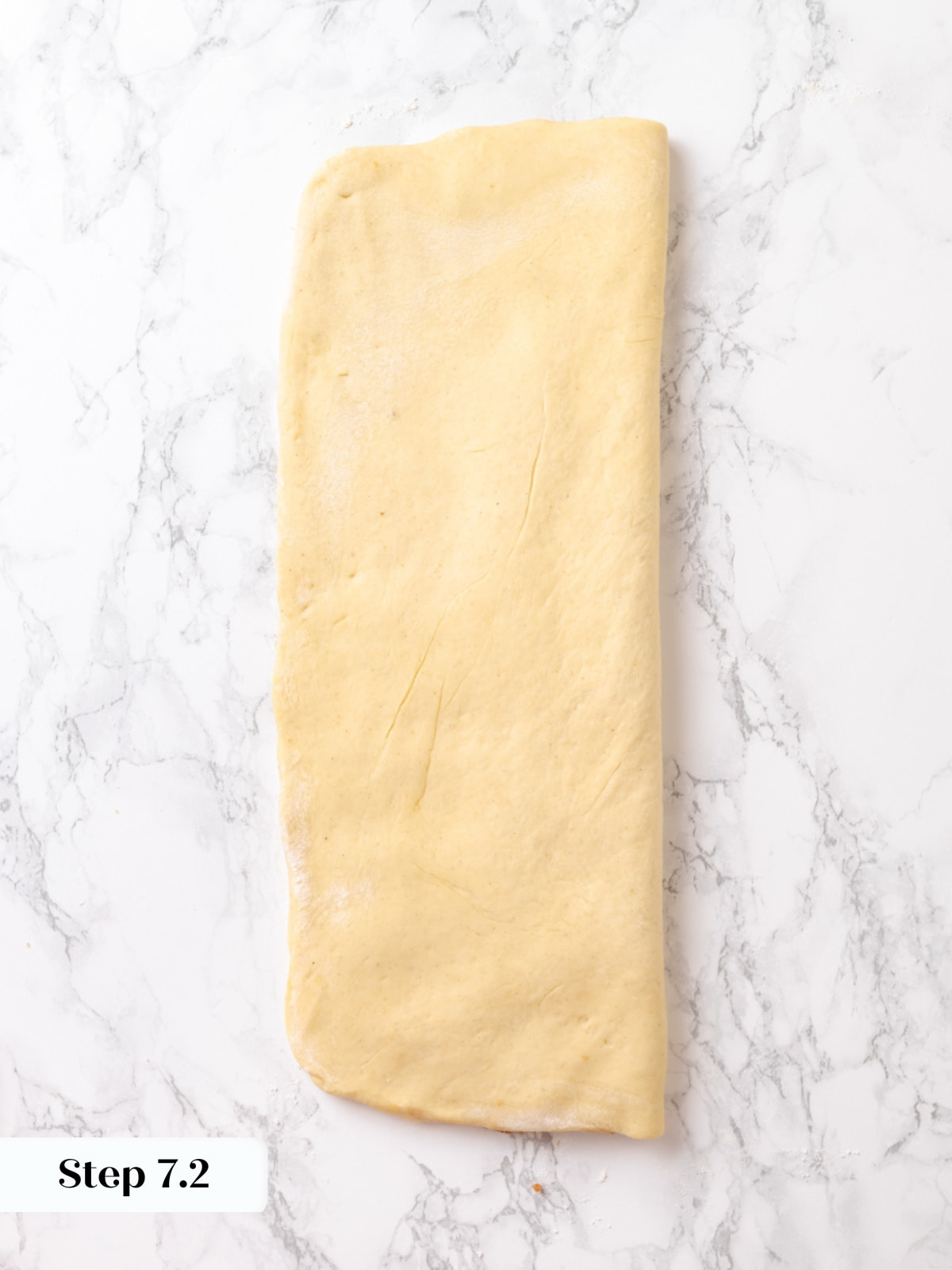 Folding dough sheet over itself to trap the cinnamon-cardamom filling between layers.