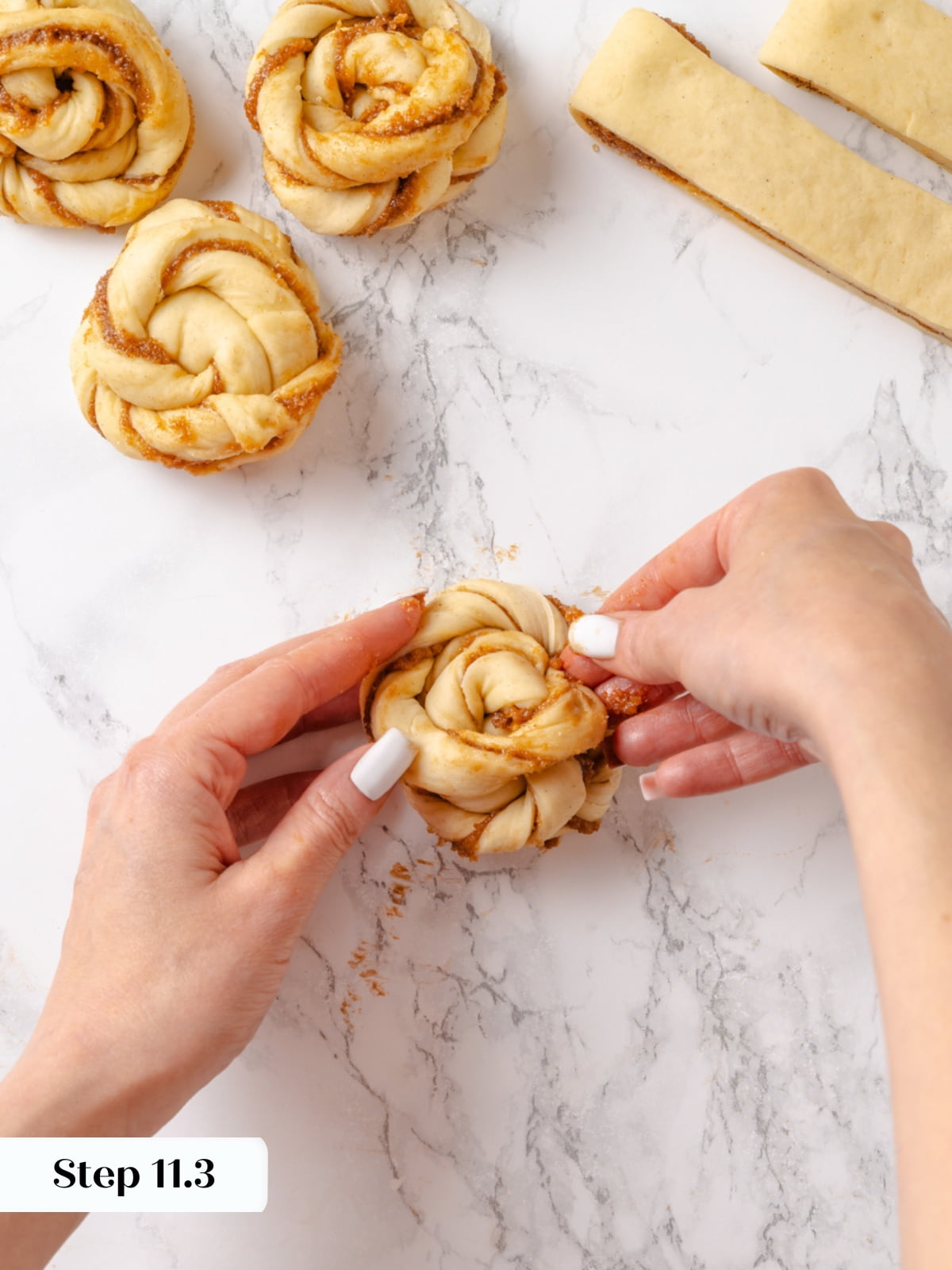 The final tuck of the left dough strand underneath to complete the cardamom bun&rsquo;s spiral.
