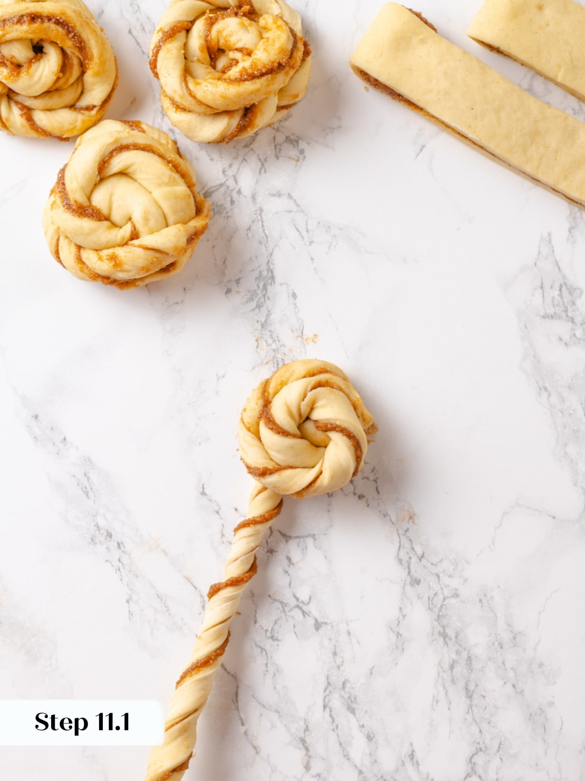 Twisting the left dough strand into a corkscrew pattern to complete the layered bun design.