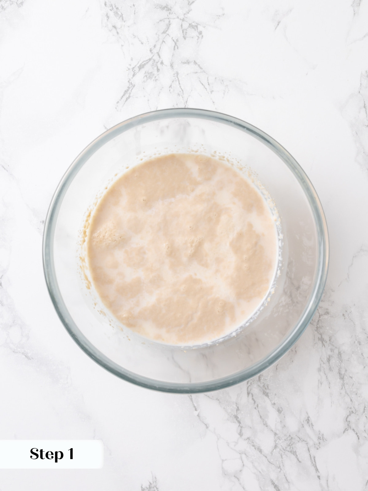 A bowl of yeast mixed with warm milk beginning to foam for the dough starter.