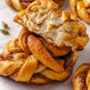 Torn cardamom bun revealing its tender interior and caramelized spiced filling inside the golden dough.
