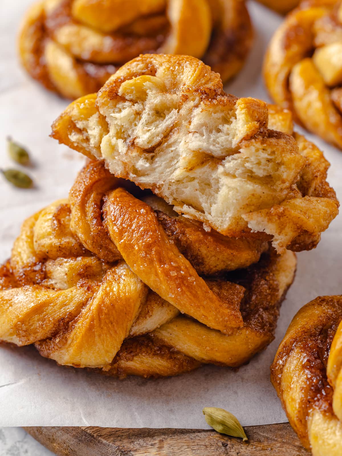 Torn cardamom bun revealing its tender interior and caramelized spiced filling inside the golden dough.