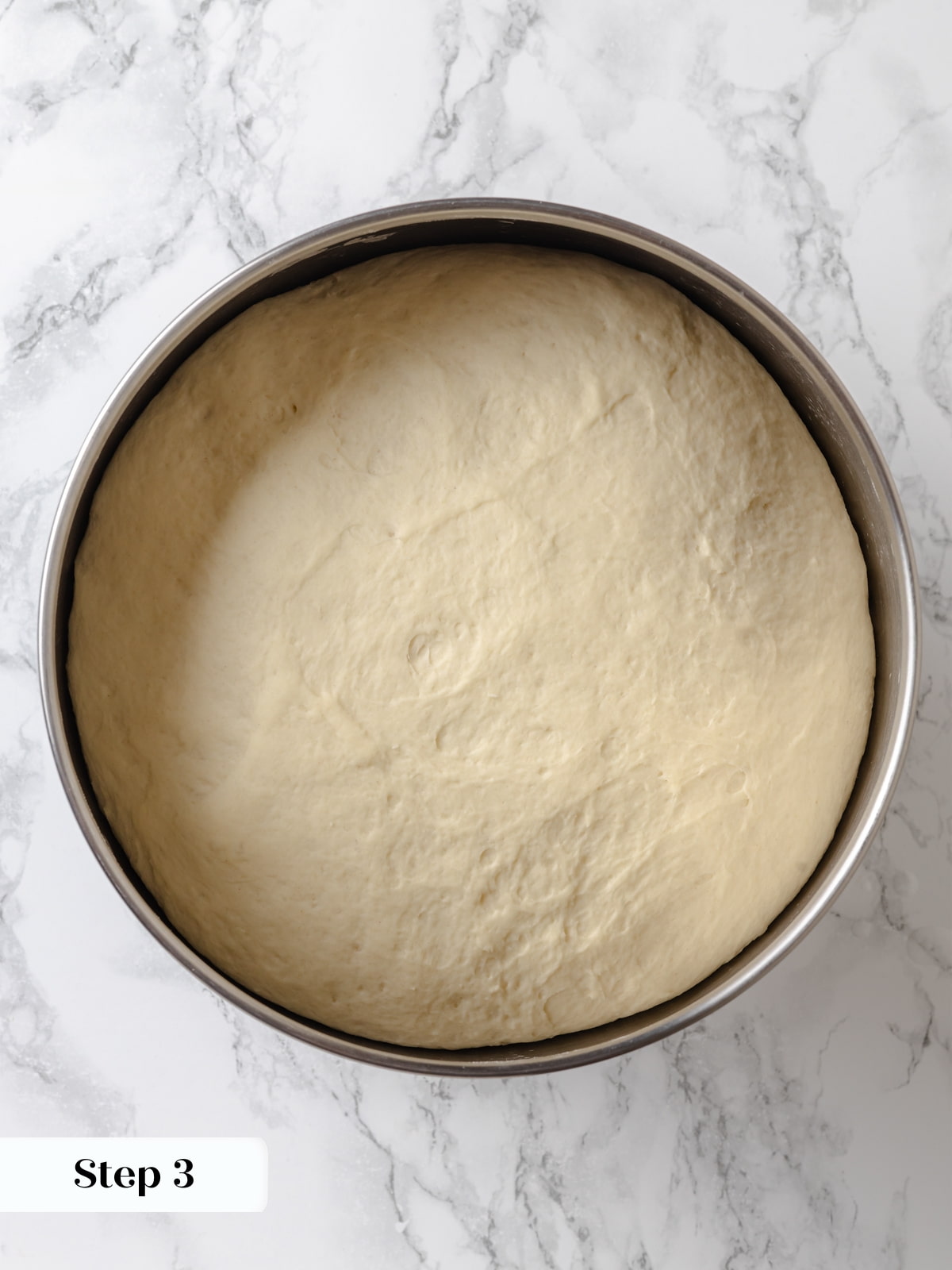 Soft dough expanded to twice its height, ready to be divided and shaped.