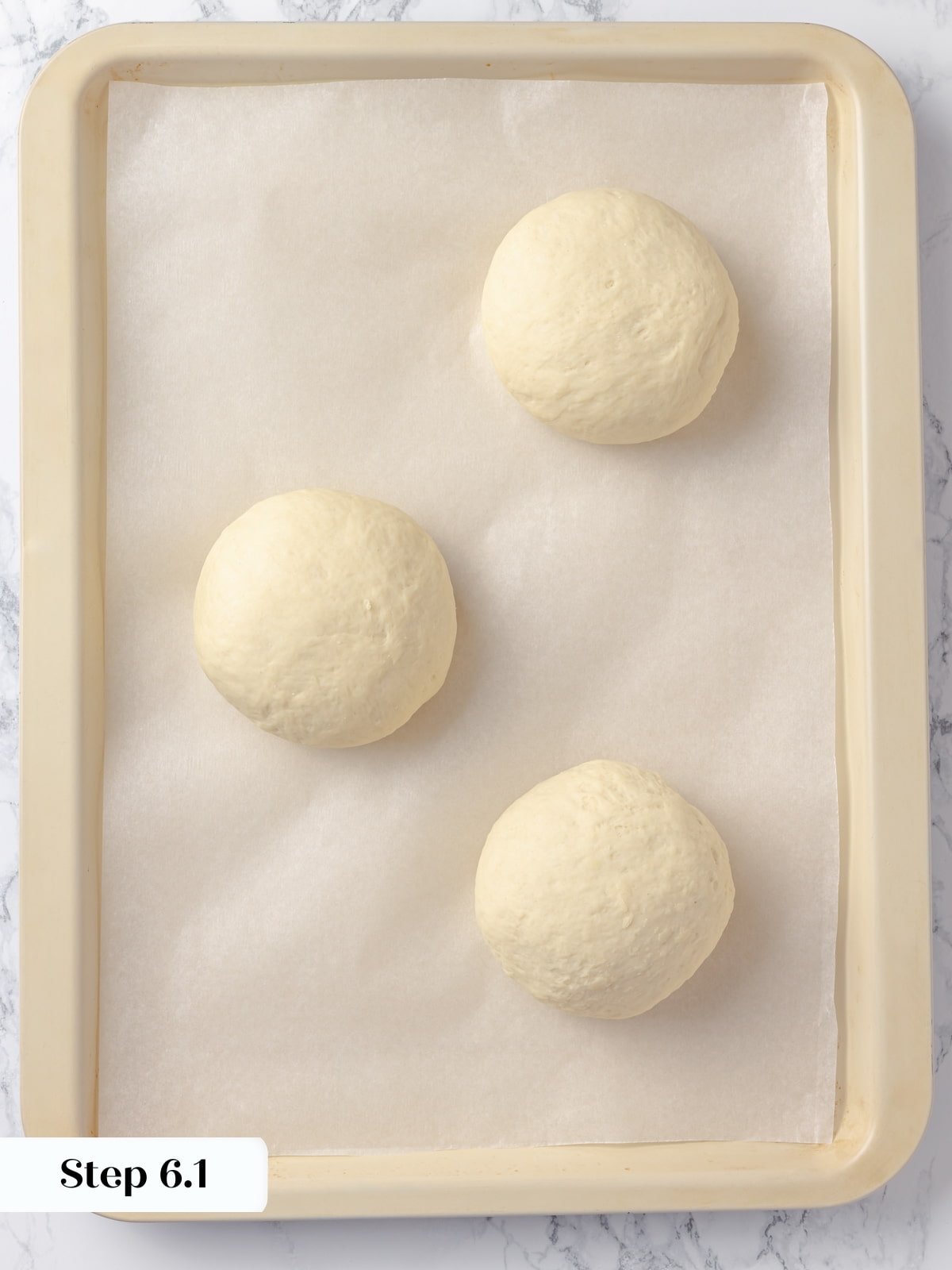 Bread bowl dough portions resting on parchment paper before being baked to golden perfection.