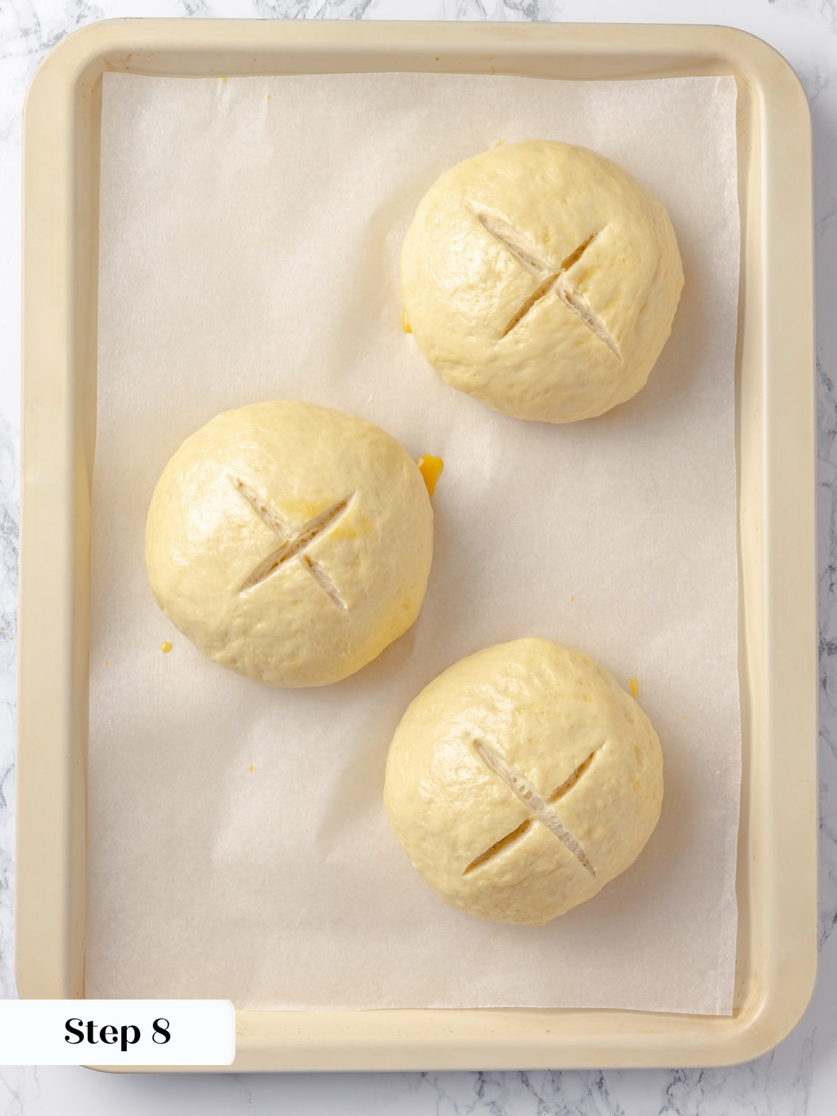 Unbaked dough marked with an X to help the bread bowls rise evenly in the oven.