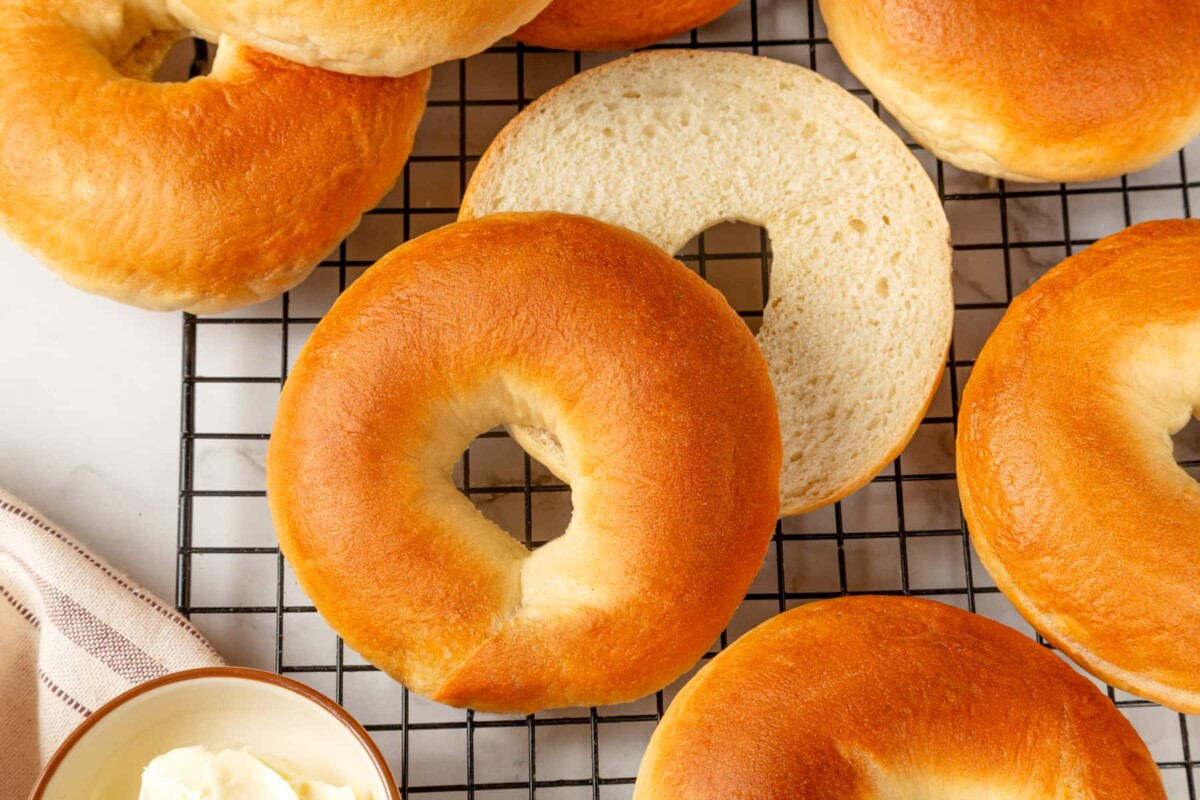 Several golden bagels resting on a rack showing firm exteriors and tender interiors.