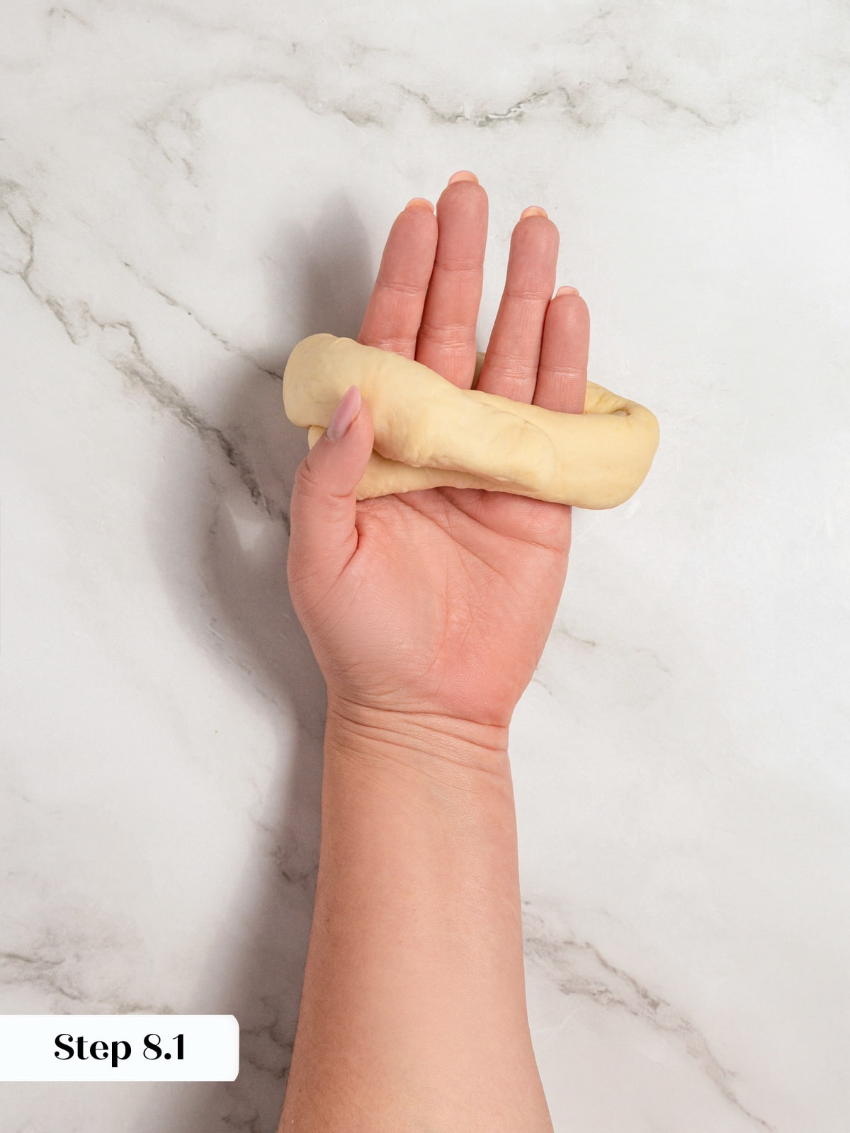 Dough rope wrapped around a hand to join the ends and form a ring shape.