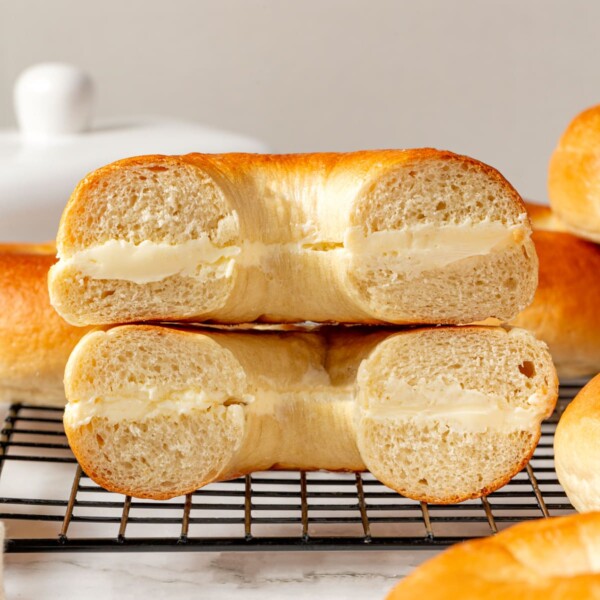 Bagel halves spread with cream cheese stacked together showing soft crumb and creamy filling.