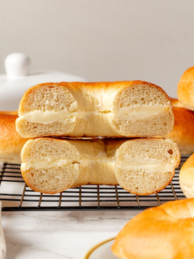 Bagel halves spread with cream cheese stacked together showing soft crumb and creamy filling.