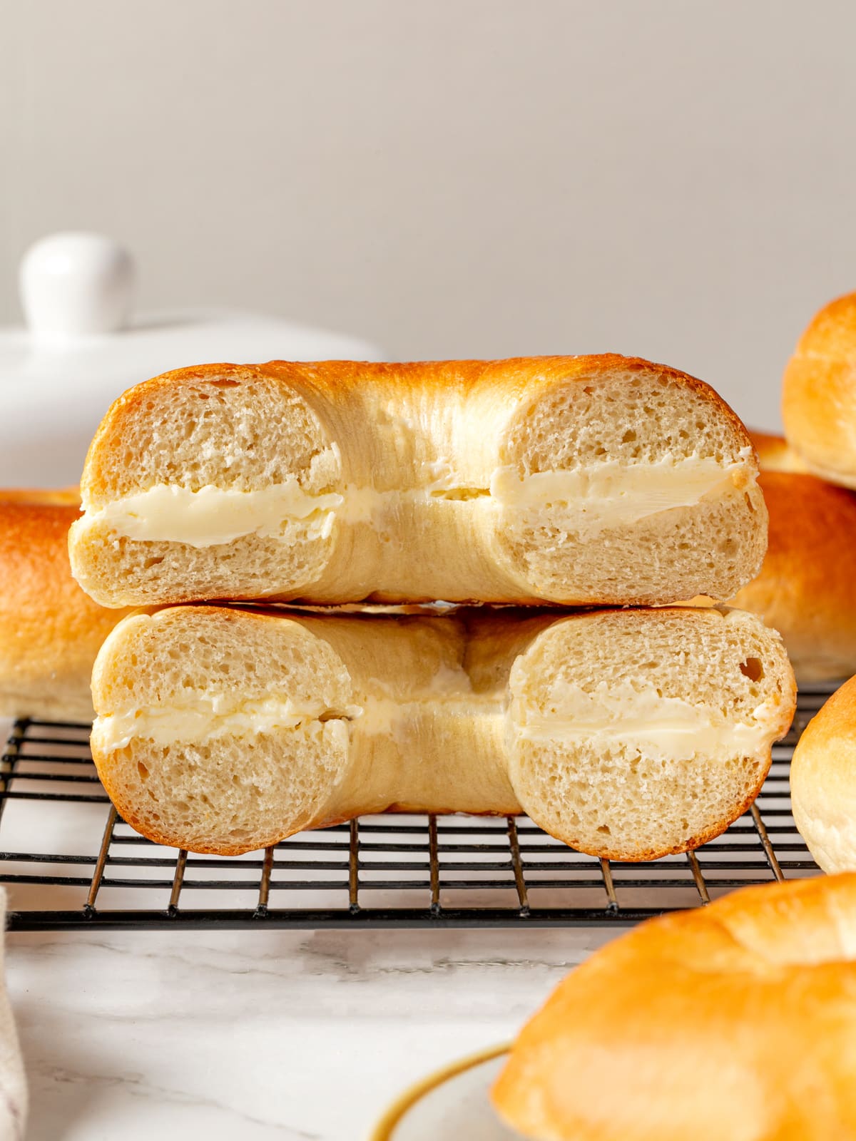 Bagel halves spread with cream cheese stacked together showing soft crumb and creamy filling.
