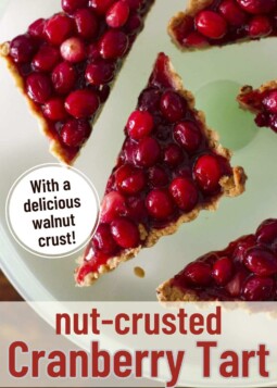 Slices of brightly colored tart with fresh cranberries and walnut crust on a plate.