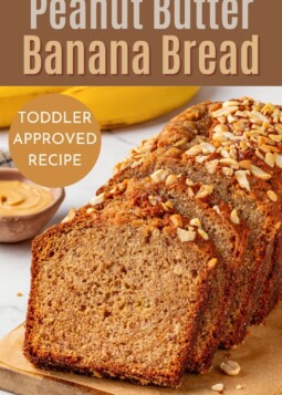 A sliced banana bread loaf made with peanut butter and ripe bananas on a wooden surface.