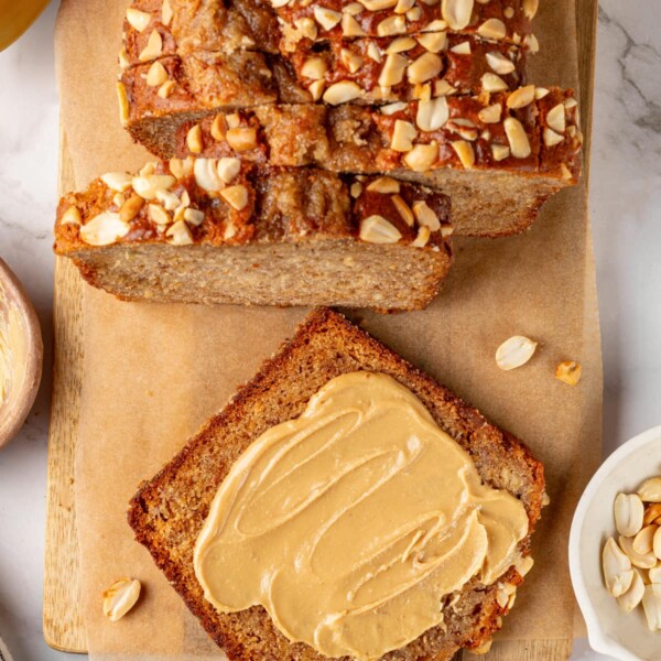 Slice of banana bread coated with creamy peanut butter for a rich, warm snack moment.