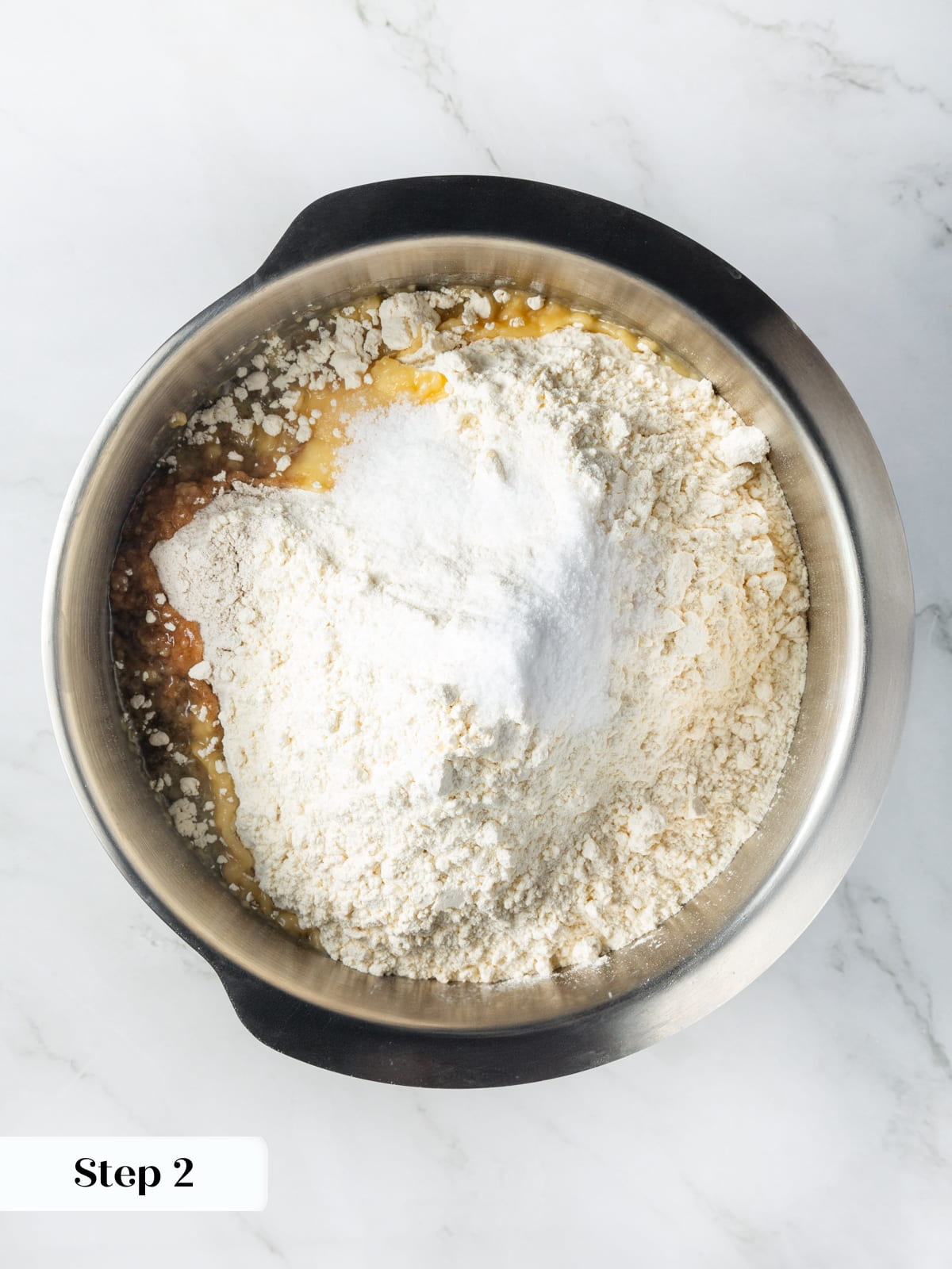 Flour, yeast, and other ingredients sitting in a mixer bowl ready to combine for dough.