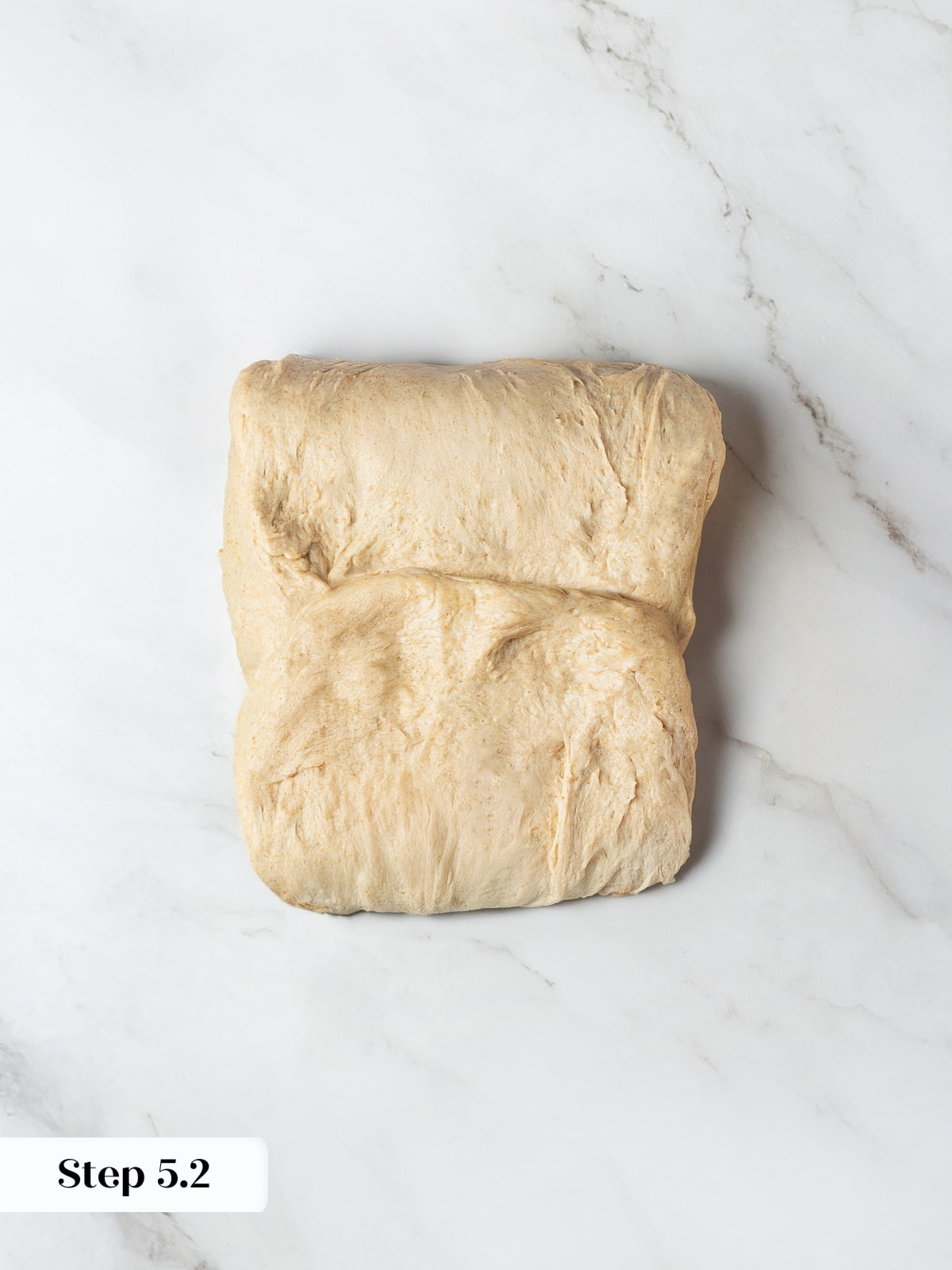 Dough being rotated and folded carefully to prepare it for forming into loaf shapes.