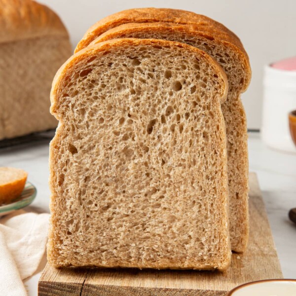 Sliced rye bread arranged neatly on a wooden board, showing a dense crumb and warm color.