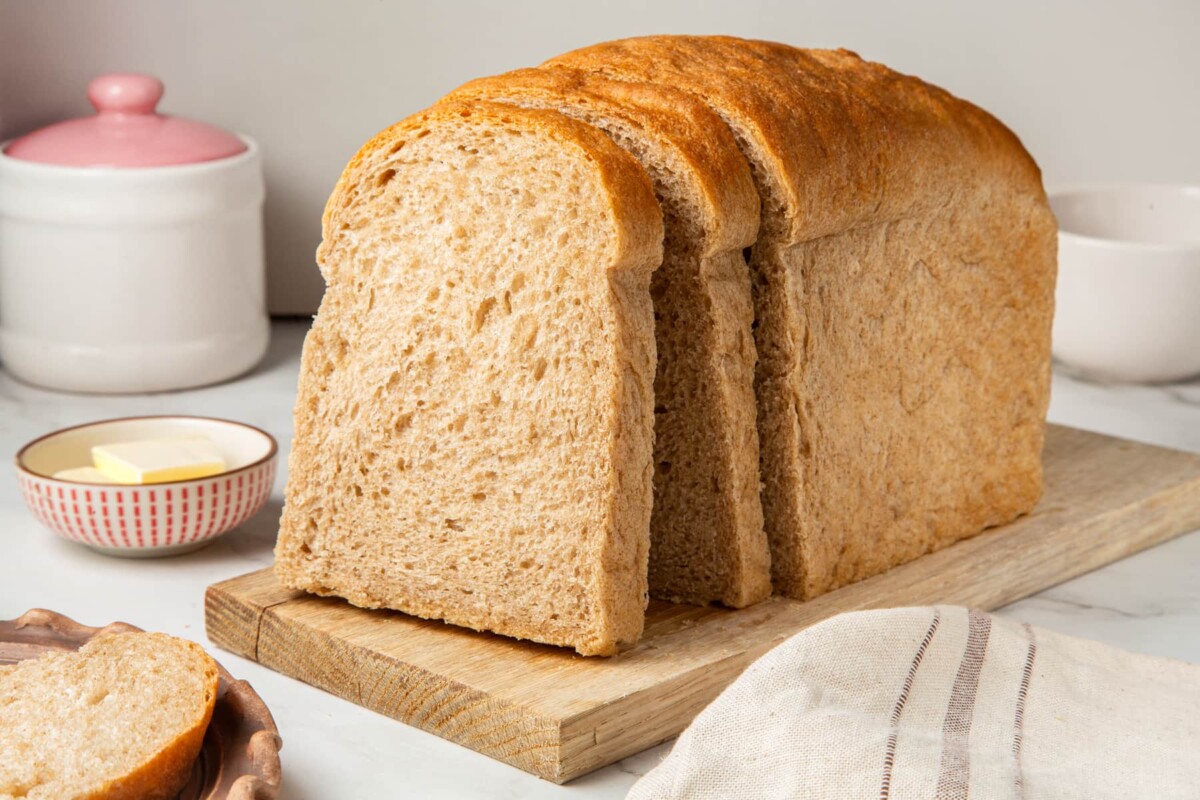 Slices of rye bread resting against the loaf, showing a soft crumb and golden crust.