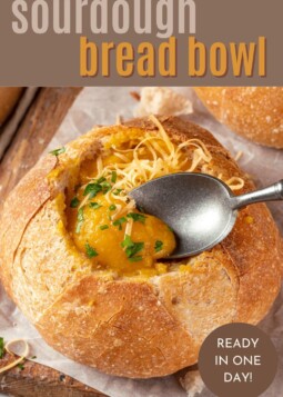 Golden sourdough bread bowl hollowed and filled with creamy soup at a cozy dinner table.