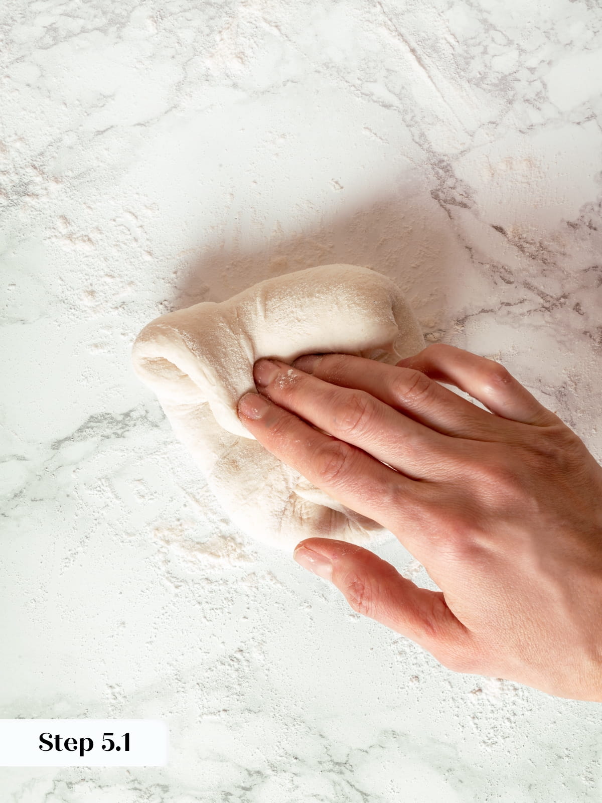 Sourdough dough folded toward center during shaping process on work surface.
