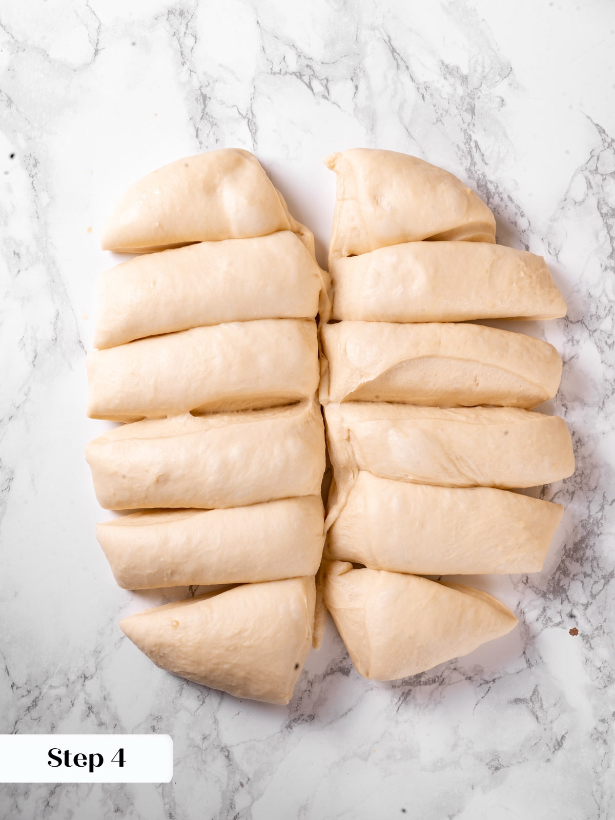 Dough divided into equal pieces on a work surface ready to be shaped into rolls.