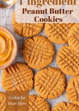 Peanut butter cookies arranged on a baking sheet with classic crisscross fork pattern.