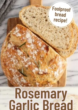 Loaf of rosemary garlic artisan bread with flaky crust cut open showing soft chewy center.