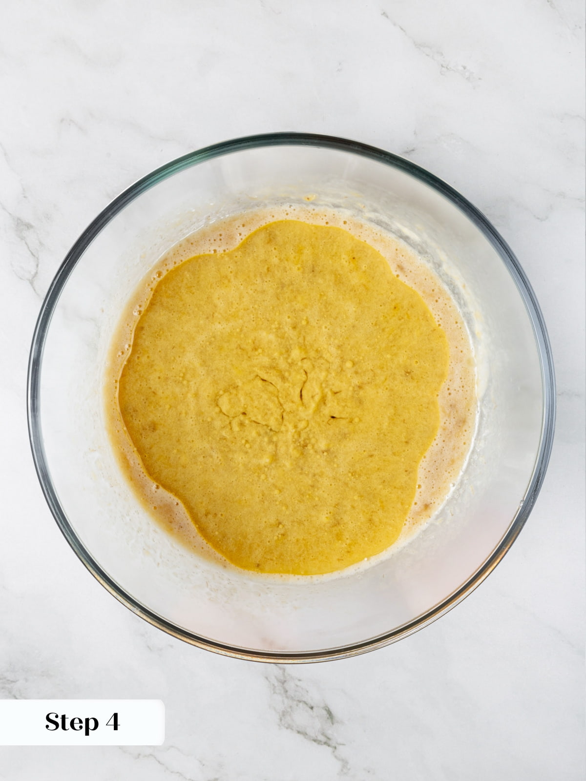 Coconut oil added to sourdough banana bread mixture in bowl before combining.