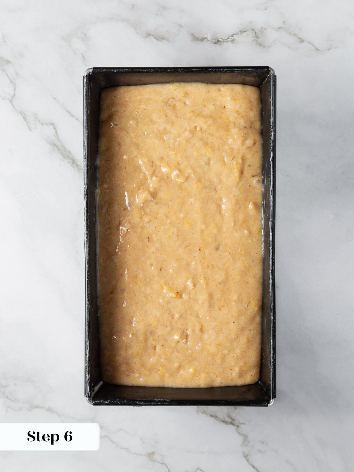 Banana bread batter poured into prepared loaf pan before baking.