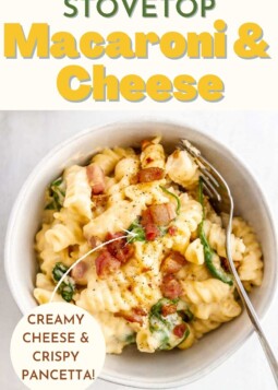 Creamy macaroni and cheese with spinach and crispy pancetta in a bowl.
