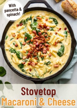Creamy macaroni and cheese with spinach and crispy pancetta in a cast iron skillet.