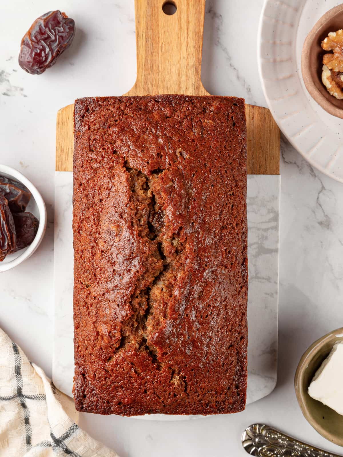 Unsliced date nut bread arranged on a cutting board for serving.