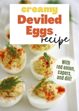 Arrangement of deviled eggs topped with paprika and dill. Text overlay reads with red onion, capers, and dill.