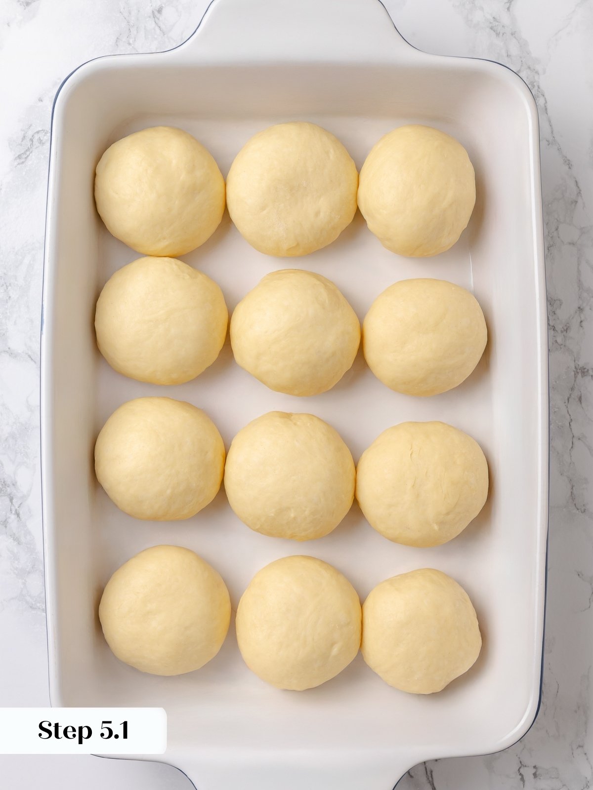 Shaped dough balls arranged in pan before final rise.