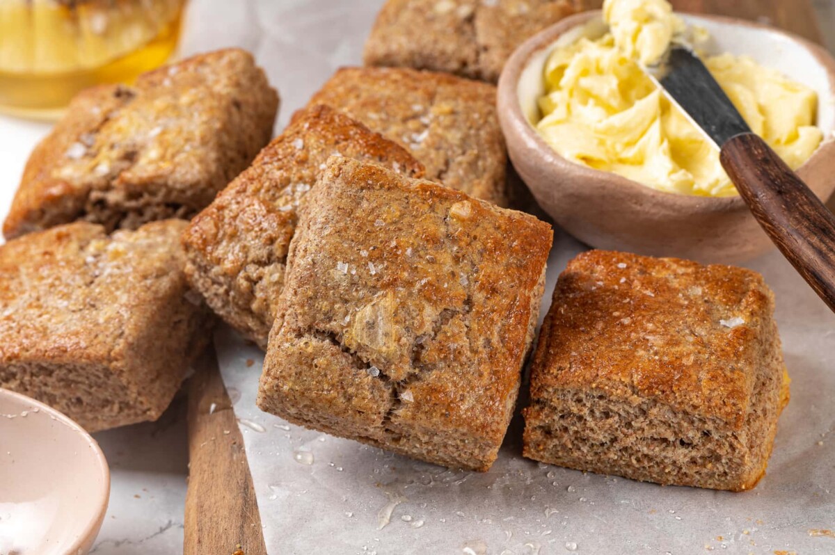 Square whole wheat biscuits arranged on parchment after baking.