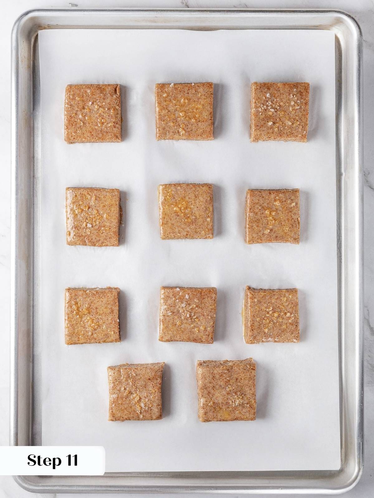Square biscuit dough pieces placed on baking sheet.