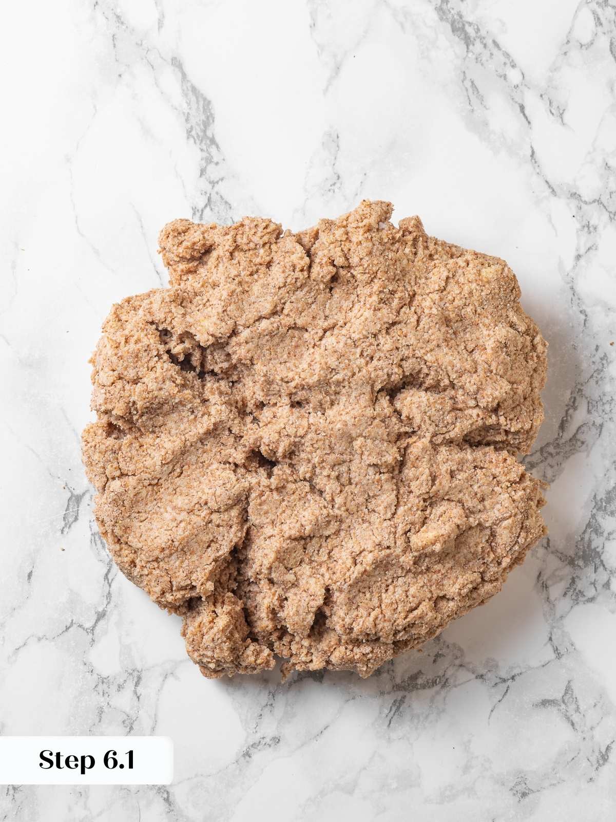 Biscuit dough being pressed flat on countertop during folding process.