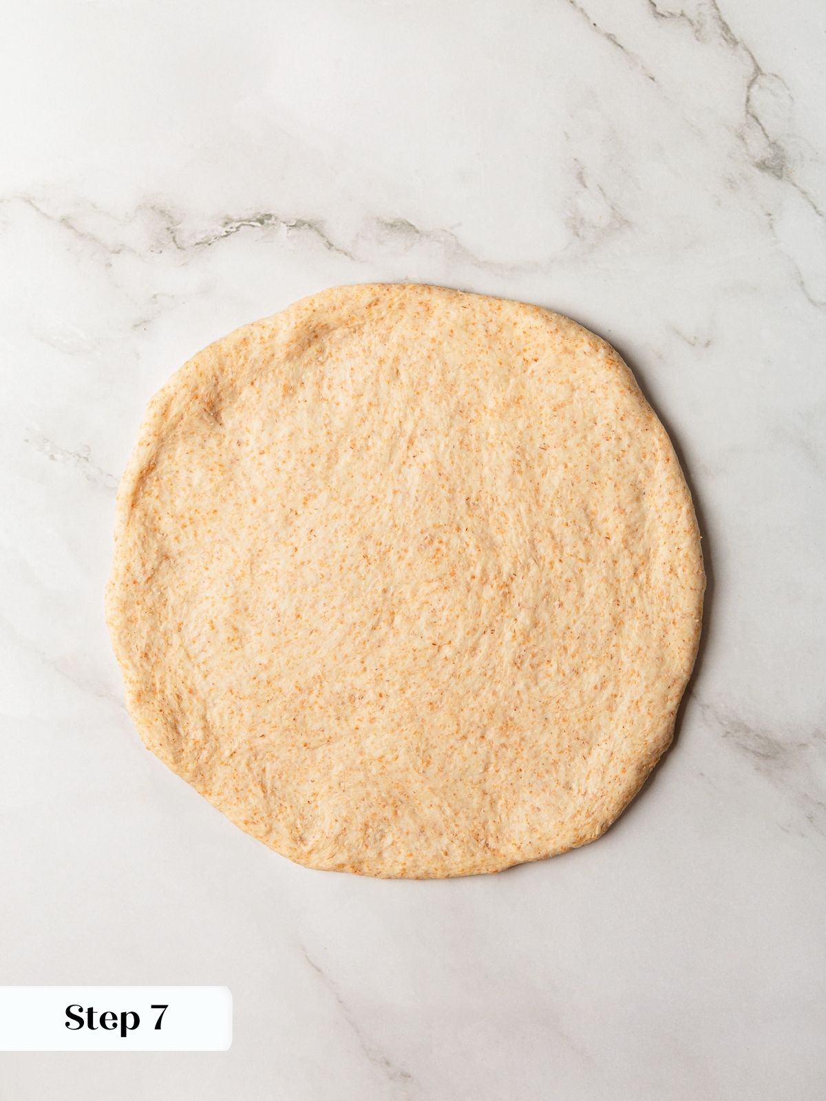 Pita dough rolled into thin round before baking.