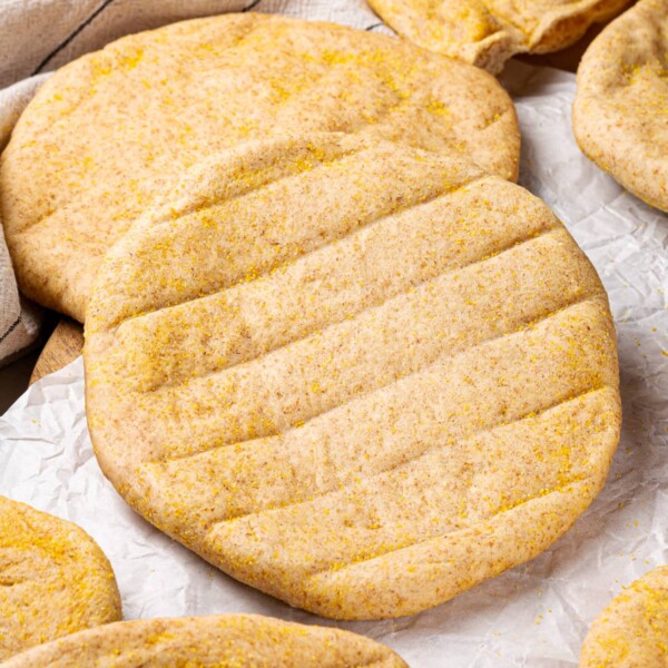 Whole wheat pitas on in white cloth to stay soft.