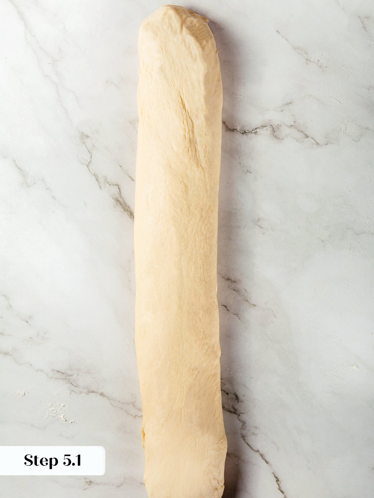 Yeast dough rolled into long log before cutting into breadstick portions.