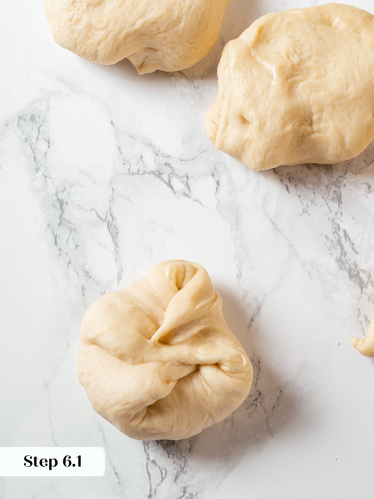 Dough edges folded into center while shaping milk bread rolls.
