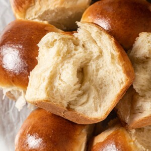 Milk bread roll ripped apart revealing stretchy fluffy crumb inside.