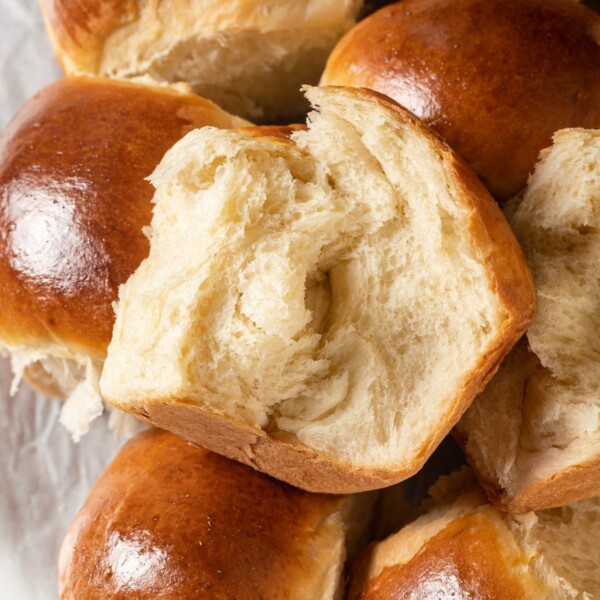 Milk bread roll ripped apart revealing stretchy fluffy crumb inside.