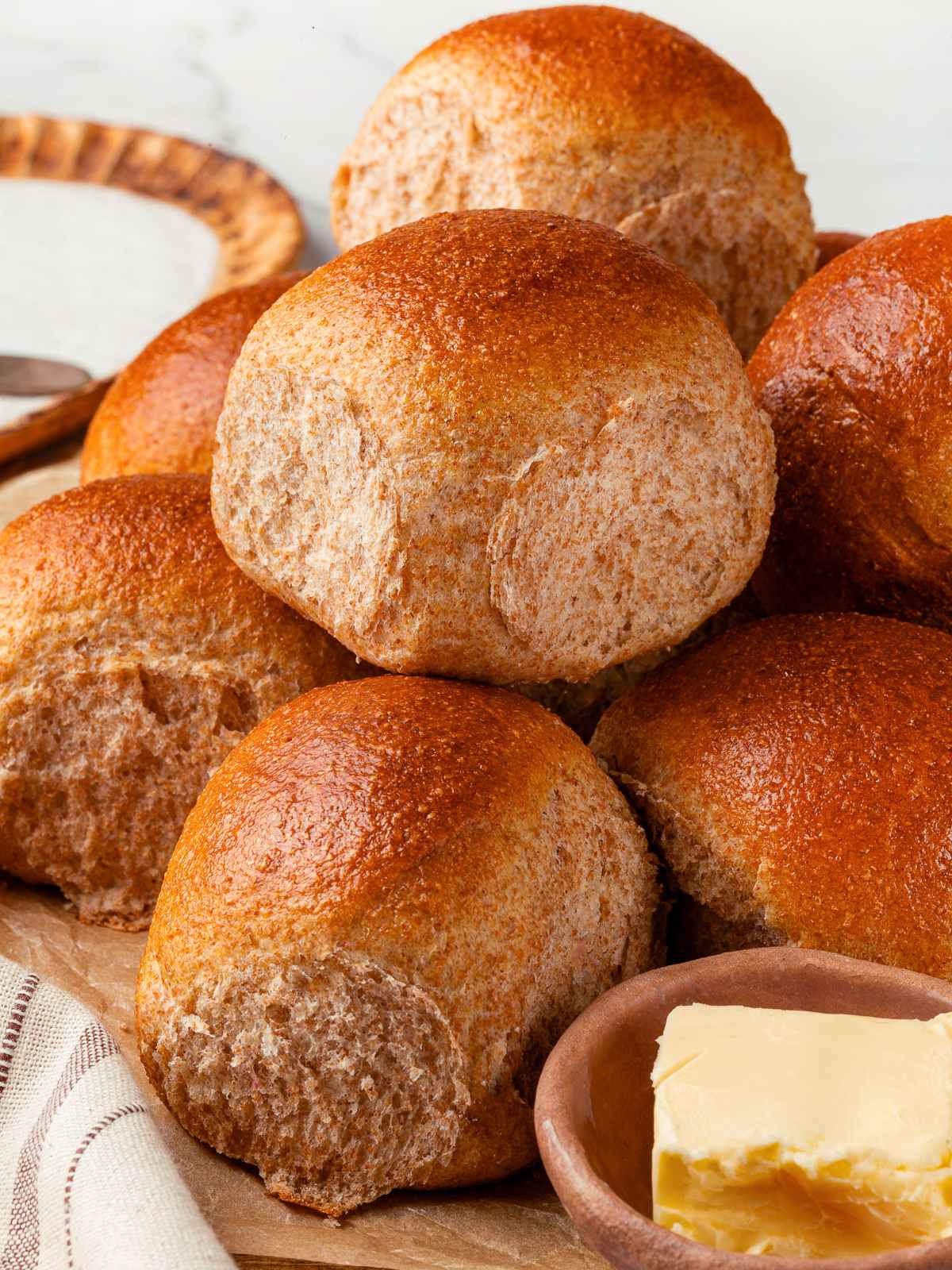 Warm whole wheat roll with square of butter ready to spread.