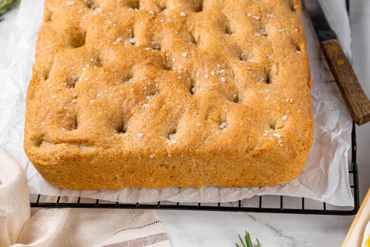 Whole wheat focaccia cooling on wire rack after baking with golden crust.