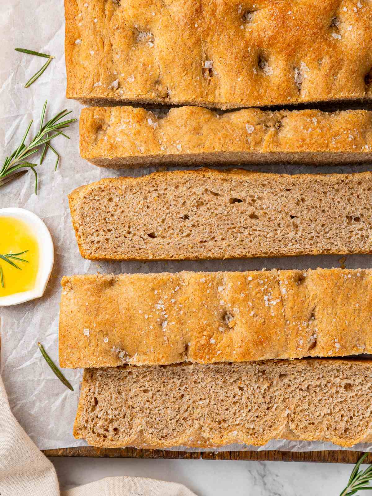 Whole wheat focaccia served with fresh rosemary and olive oil after baking.