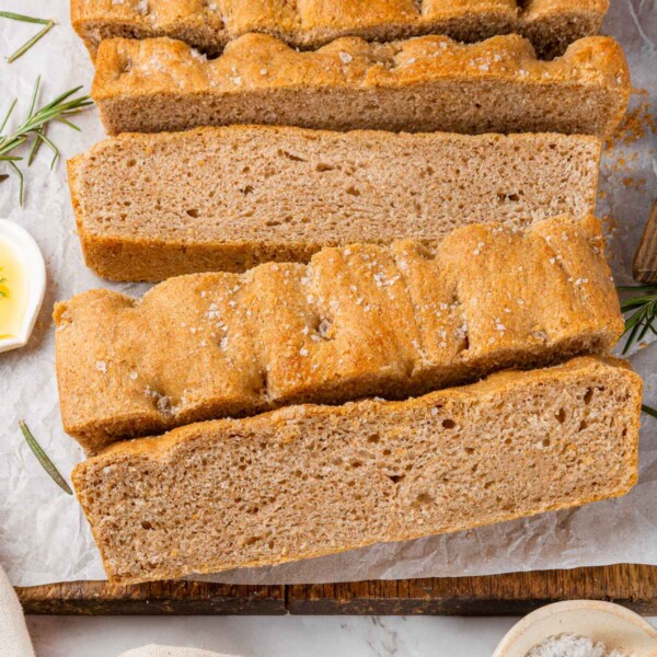 Whole wheat focaccia baked on parchment paper with golden crust and crisp edges.